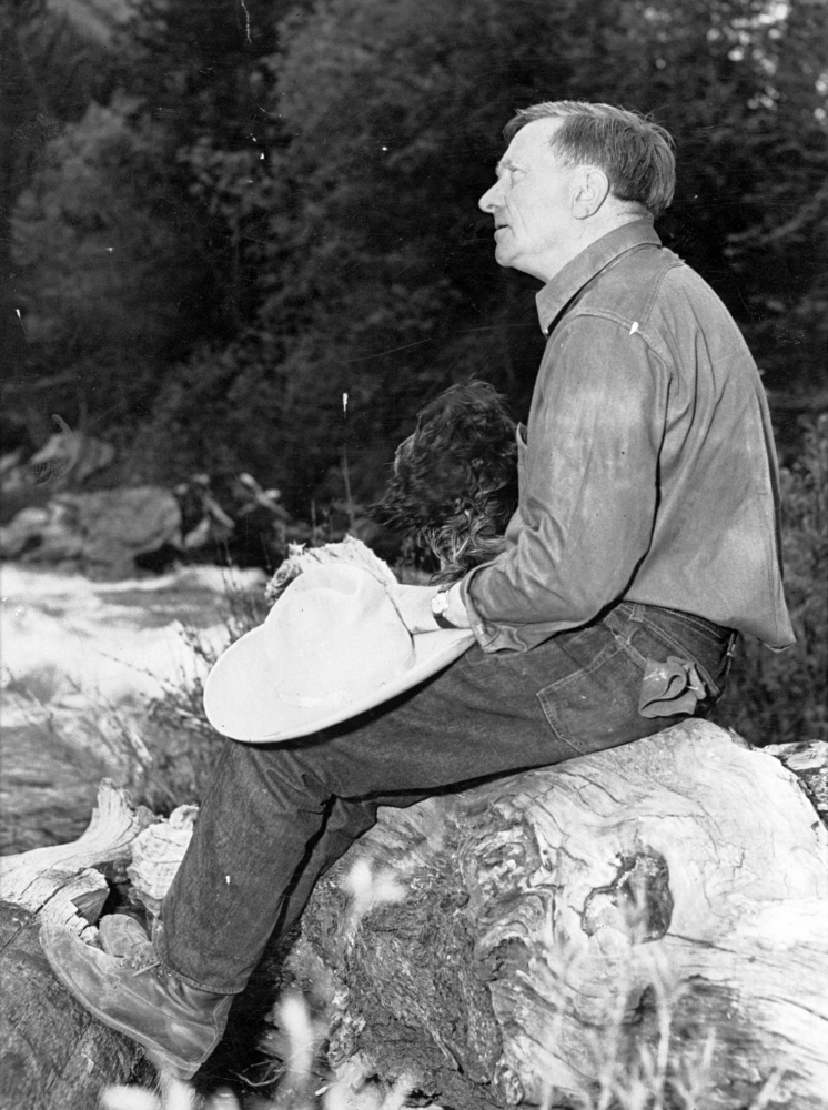 Justice William Orville Douglas and his dog rest on a log near his Lostine, Oregon, cabin.