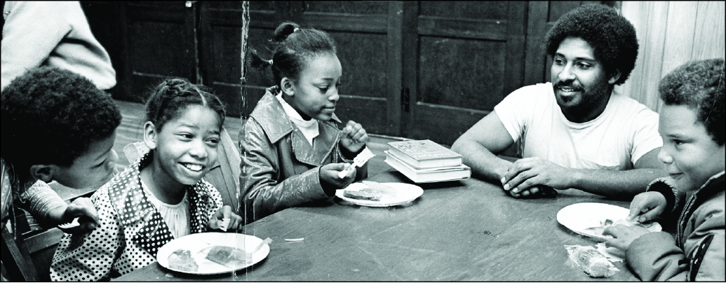 Children at the Black Panthers' free breakfast program, 1971. Kent Ford sits with the children.